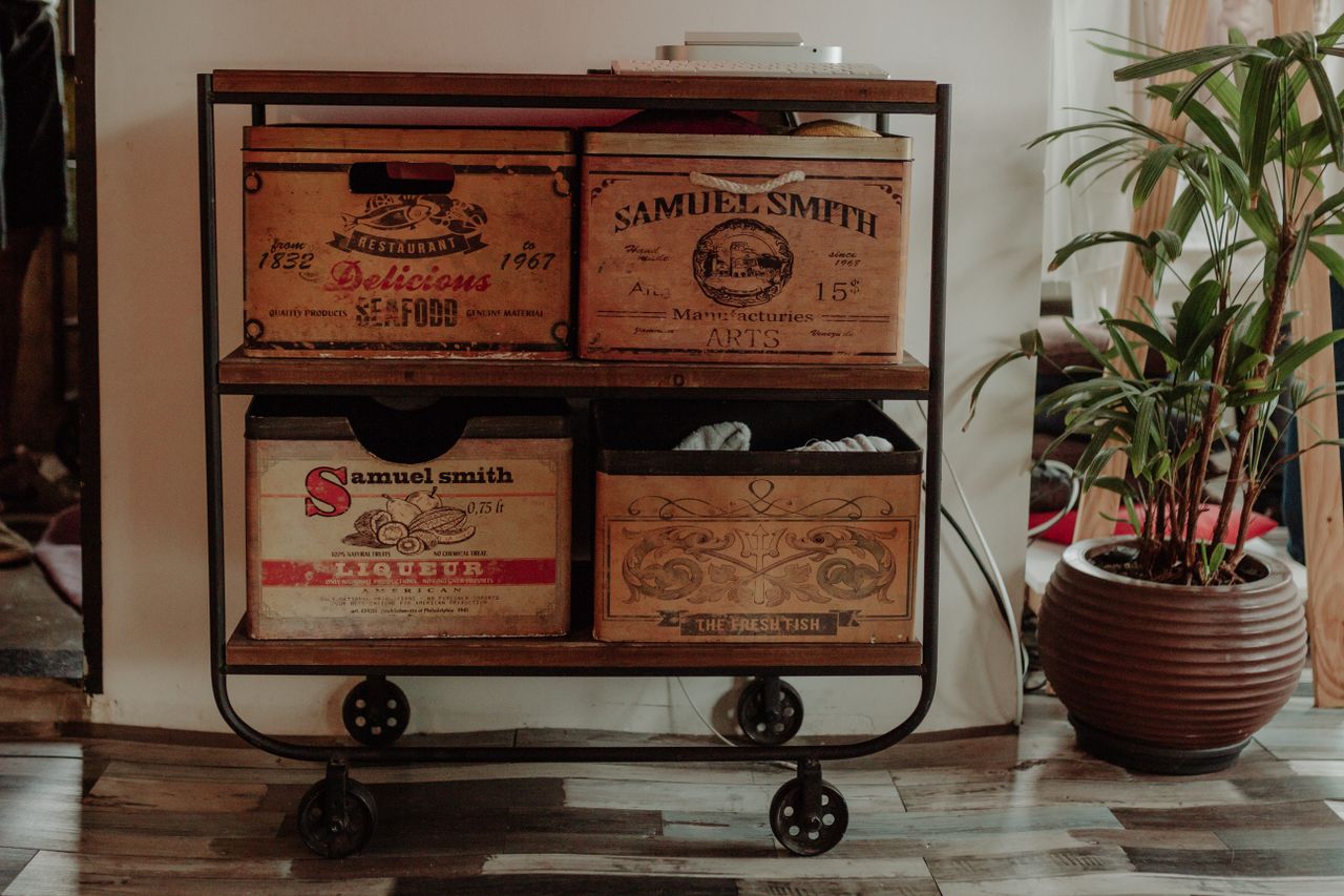 A stylish industrial cart with vintage wooden boxes next to a potted plant indoors.